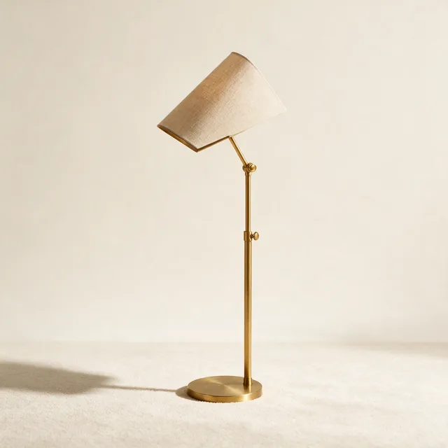 A slim floor reading lamp with a brass stem and a linen shade