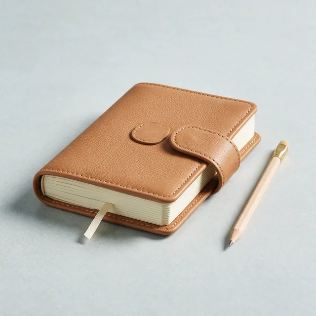 A closed reading journal with a ribbon marker and pencil
