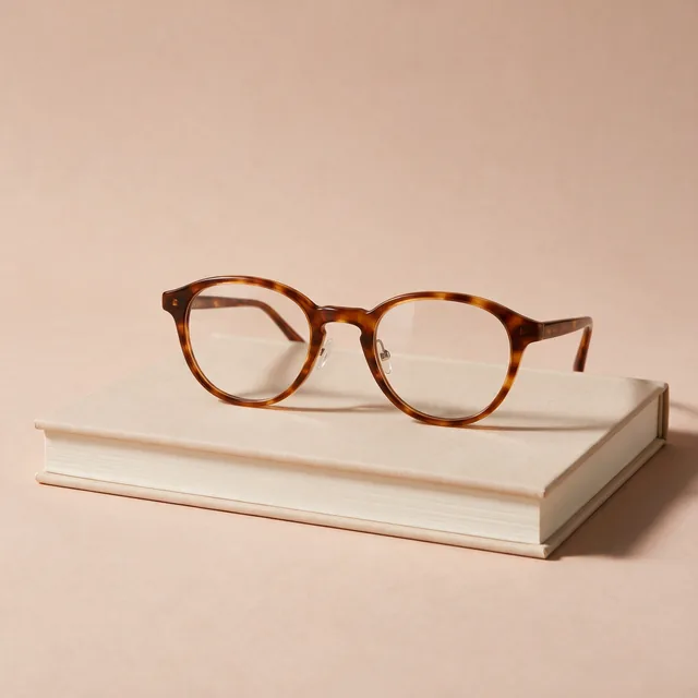 Tortoiseshell reading glasses resting on a closed book